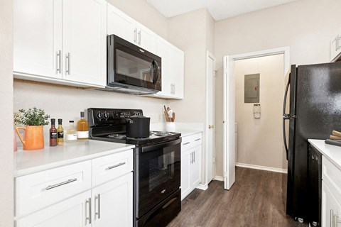 a kitchen with white cabinets and black appliances and a black refrigerator at Canyon Creek, Austin, TX